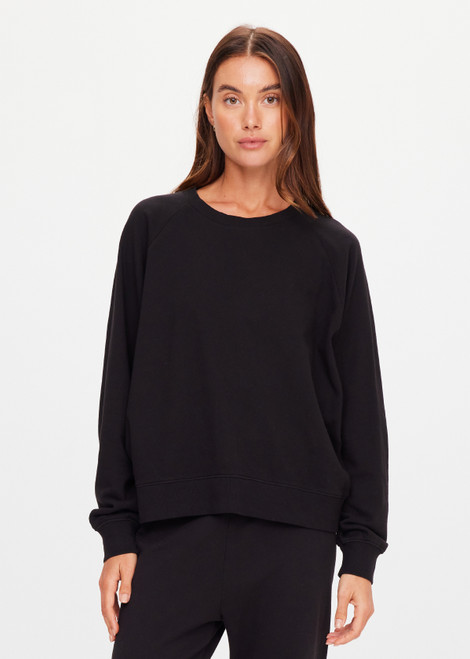 THE UPSIDE women's black organic cotton Lennox Raglan Crew Sweater offers a relaxed fit and features a classic crew neckline, ribbed. cuffs and hem. Finished with a subtle embroidered arrow logo at back. The perfect everyday sweater, made to last.