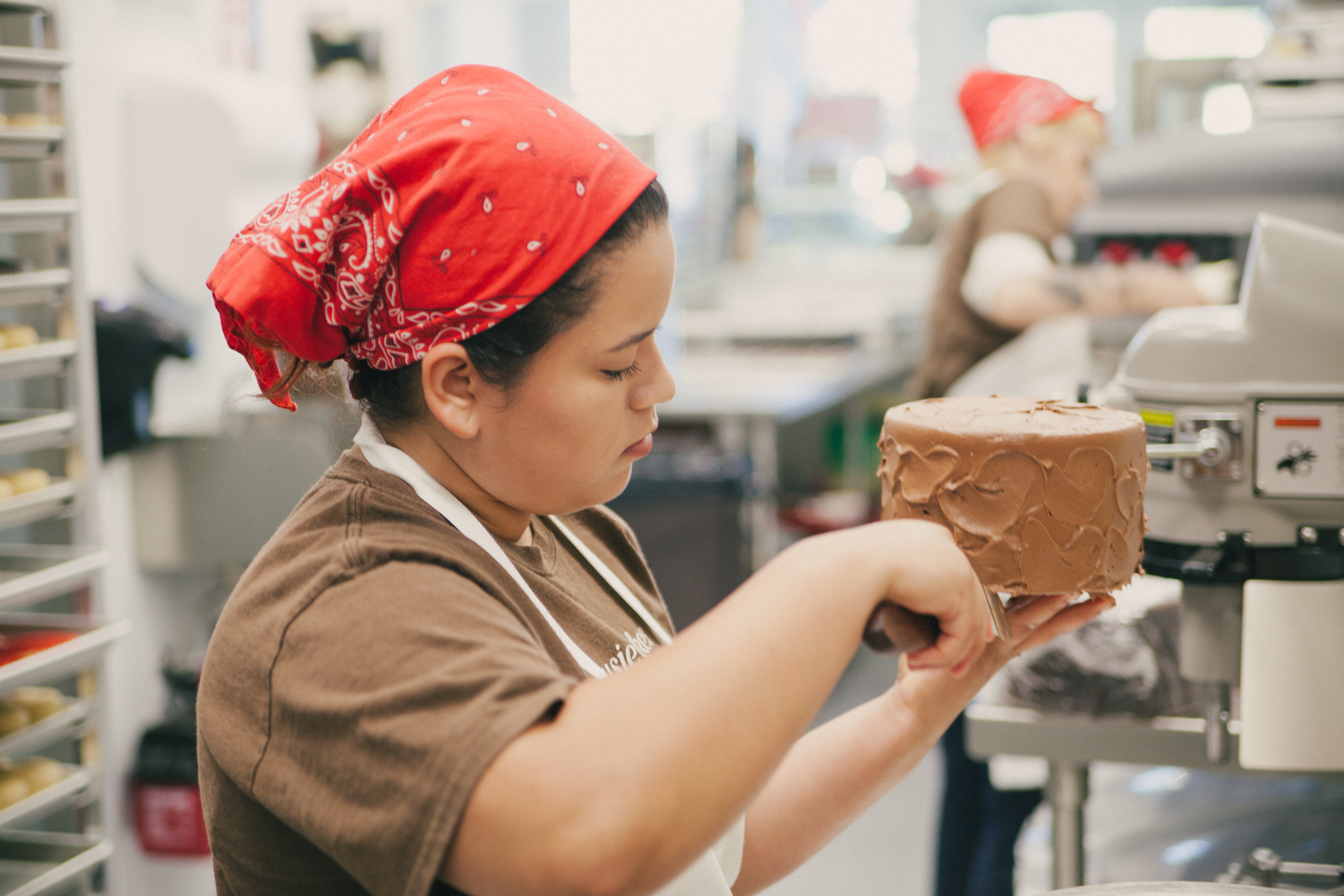 Baker icing a chocolate cake.