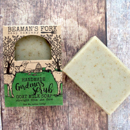 Gardener’s Scrub Goat Milk Soap bar with pumice and fresh basil leaves on a rustic wood surface