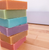 Six unboxed goat milk soap bars arranged together in a stack on a wood table