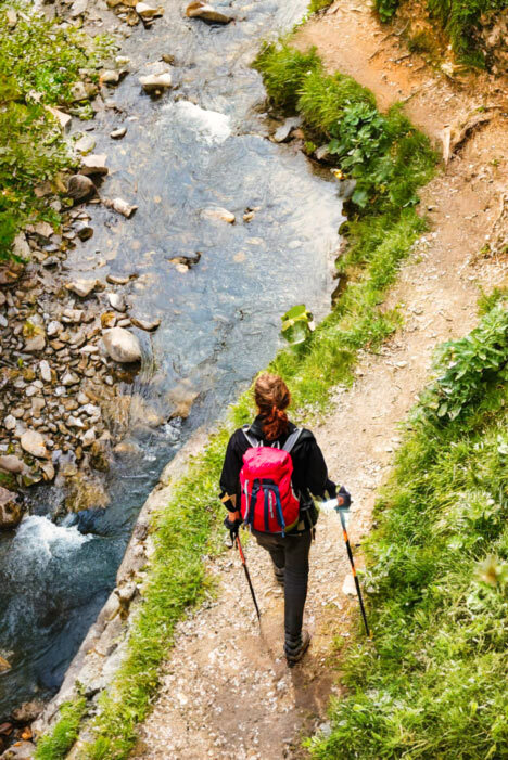 Female hiker on a coffee journey walking along a creek