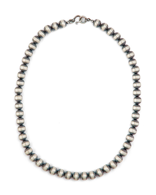 Large silver bead necklace resting on white surface, elegant and versatile.