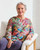 Woman wearing the potpourri top, highlighting its flattering shape and vibrant pattern. View Product Image