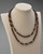 Garnet beaded necklace displayed on a mannequin highlighting polished metal and beads. View Product Image