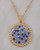 Gold pave necklace with blue and white crystals on a marble surface. View Product Image
