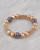 Gold-tone pavé crystal bracelet with blue accents displayed on a marble surface. View Product Image