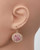 Gold with sparkly pink crystal earrings on a mannequin's ear, elegantly showcasing its radiant design. View Product Image