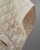 Close-up of a cream quilted poncho cape showing textured fabric and snap buttons. View Product Image