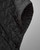 Close-up of a black quilted poncho jacket with button details. View Product Image