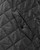 Close-up of a black quilted poncho cape showing a buttoned pocket detail. View Product Image