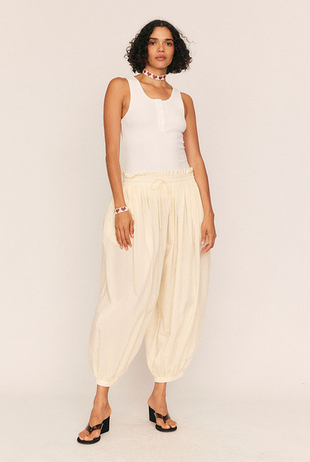 Breezy, billowing, and beautifully undone. The Genie Pant in soft Buttermilk is your invitation to float through the day with ease. Crafted from lightweight cotton voile, this ankle-grazing silhouette features a smocked elastic waist and cuffs for all-day comfort, while a waist drawcord and side seam pockets add subtle functionality.