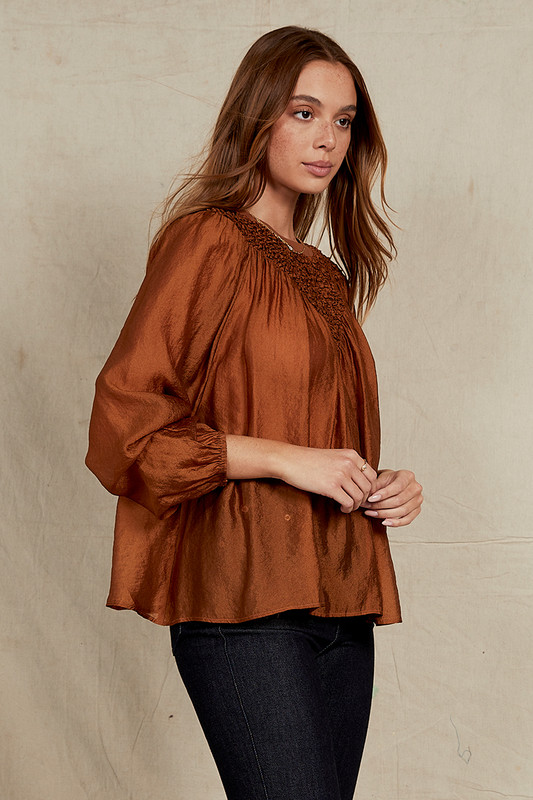 Elevate your wardrobe with our Bronze Crew Neck Blouse. Effortlessly chic, this long-sleeve blouse combines classic design with modern flair. The shirring detail on the front adds texture and dimension while tempering the ethereal sheerness. Wear yours with denim and strappy sandals.