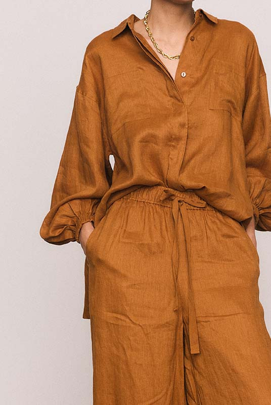 These rust linen wide-leg pants combine effortless comfort with elevated tailoring. The elasticated waist with drawcord and side pockets create a laid-back yet polished silhouette, perfect for both sunlit mornings and twilight dinners. Wear with the Rust Billow Shirt for easy, relaxed style.