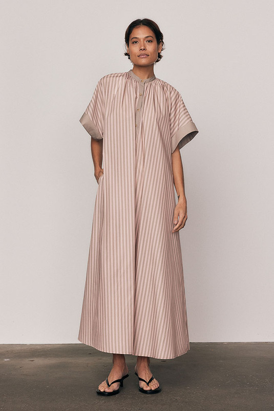 Crisp cotton poplin meets effortless movement in the Maxi Smock Dress. Showcasing Bohemian Traders’ custom pink striped print, this dress balances structure with ease through wide sleeves and a fluid silhouette. Designed to flatter every form, it’s the ultimate throw-on piece for sunny days and easy evenings.