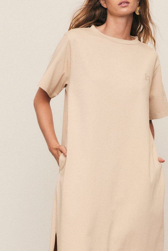 The T-Shirt Dress is crafted from premium pure cotton with subtle logo embroidery, delivering everyday comfort with refined simplicity. Designed in an oversized silhouette with side splits and pockets, it moves effortlessly through the day. Easy to wash and endlessly wearable, this natural-fibre essential defines the art of relaxed, elevated dressing.