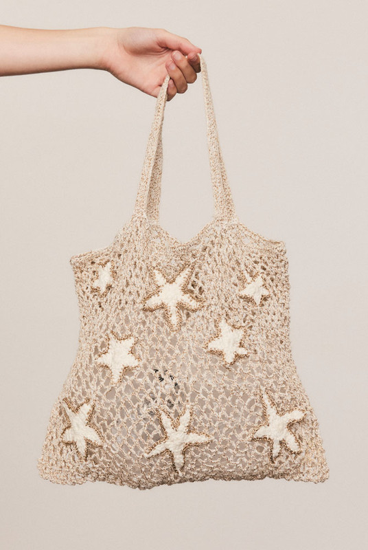 Hand-crocheted from cream cotton with a touch of gold lurex, this small tote features an intricate shell motif and soft structure—an artful accent for sunlit, effortless days.