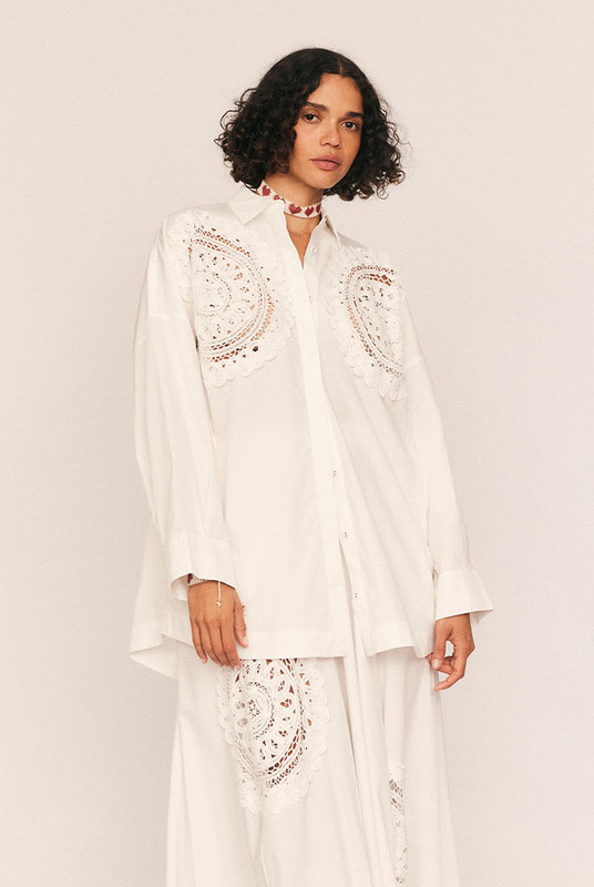 A fresh interpretation of feminine tailoring, the Crochet Oversized Shirt blends crisp structure with delicate detail. Crafted from pure cotton poplin in clean white, its oversized silhouette is elevated by intricate lace crochet at the chest—an artisanal touch that nods to vintage romance.