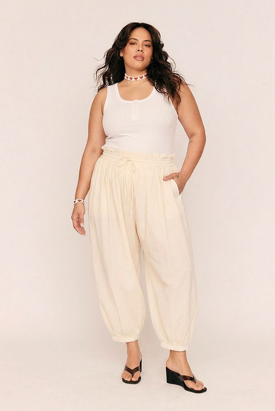 Breezy, billowing, and beautifully undone. The Genie Pant in soft Buttermilk is your invitation to float through the day with ease. Crafted from lightweight cotton voile, this ankle-grazing silhouette features a smocked elastic waist and cuffs for all-day comfort, while a waist drawcord and side seam pockets add subtle functionality.