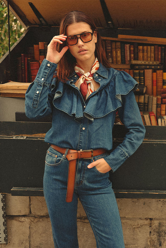 A timeless staple with a romantic edge, the Ruffle Denim Shirt redefines denim shirting with soft structure and thoughtful detail. Crafted from premium mid-weight cotton denim, it features a circular frill tracing the front and back yoke—bringing movement and femininity to a classic silhouette.