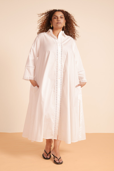 Pure and poetic, this maxi shirt dress in crisp cotton poplin combines classic structure with delicate lace inserts. The Lace Opera Shirt Dress drapes loosely with long sleeves and cuff details, side pockets, and a collar for refined ease. It’s a romantic layer of light, perfect for slow afternoons and summer evenings.