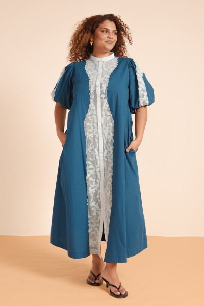 The Legion Shirt Dress is a study in soft structure made from crisp cotton poplin with delicate lace applique and balloon sleeves. Slightly fitted at bust and waist, it’s finished with side pockets and a mandarin collar for a timeless silhouette with a feminine twist. It exudes Sicilian charm, perfect for long lunches, afternoon strolls and aperitivo.