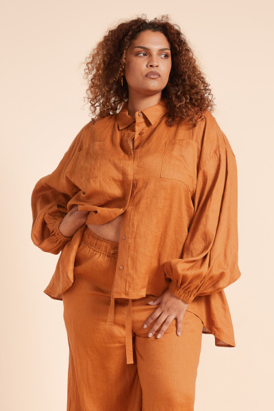 The Billow Shirt drapes beautifully with a high-low hem, balloon sleeves, and chest patch pockets. Crafted from pure linen in a warm rust tone, it’s a softly structured piece that embodies relaxed, sun-soaked sophistication. Pair with the matching pant for effortless dressing.