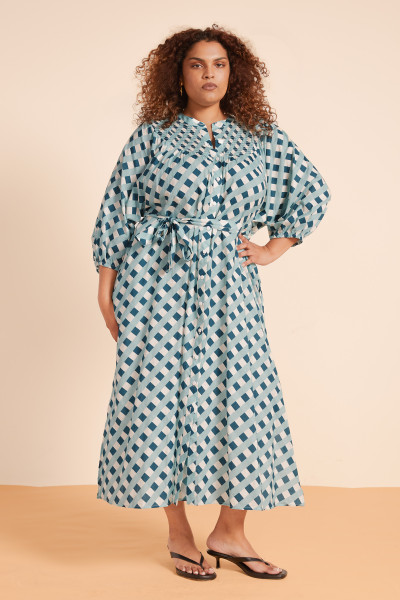 Light cotton voile meets classic print in the Checkers Smocked Dress. Balloon sleeves, mandarin collar, and a tie waist shape a silhouette that’s equally at home on warm walks or late summer dinners. Soft, breathable, and effortlessly chic.