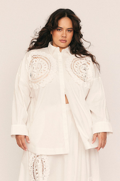 A fresh interpretation of feminine tailoring, the Crochet Oversized Shirt blends crisp structure with delicate detail. Crafted from pure cotton poplin in clean white, its oversized silhouette is elevated by intricate lace crochet at the chest—an artisanal touch that nods to vintage romance.