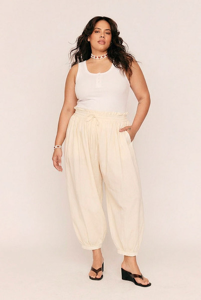 Breezy, billowing, and beautifully undone. The Genie Pant in soft Buttermilk is your invitation to float through the day with ease. Crafted from lightweight cotton voile, this ankle-grazing silhouette features a smocked elastic waist and cuffs for all-day comfort, while a waist drawcord and side seam pockets add subtle functionality.