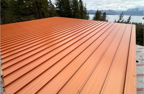 Copper-coloured standing-seam metal roof with a lake behind