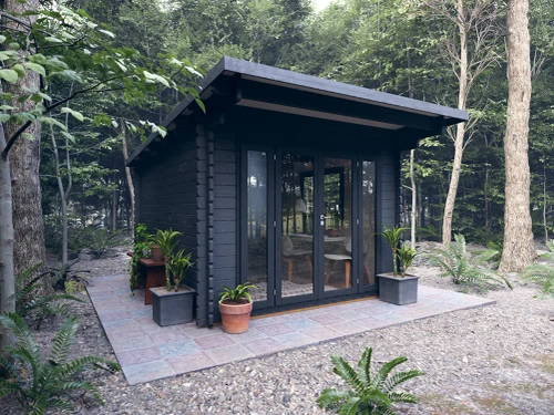 Modern wood shed studio installed in a lush backyard garden with contemporary landscaping.
