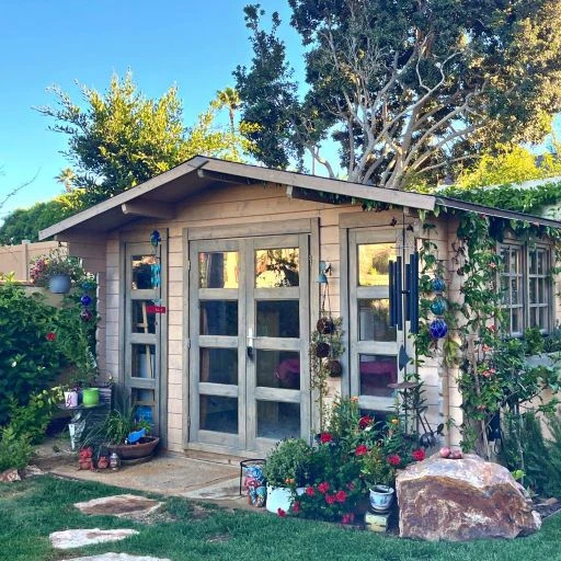 A beautifully styled solid wood garden cabin shed in a planted backyard