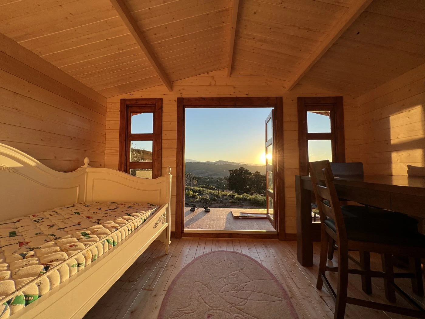 Warm wood cabin interior glowing with sunset light through open doors