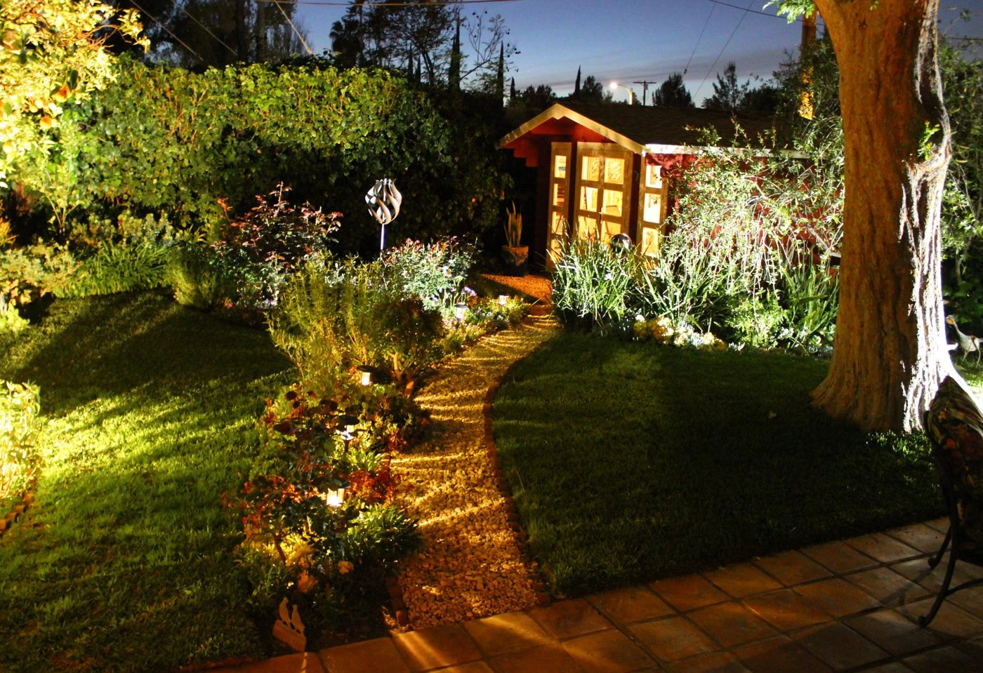 Warmly lit studio shed at the end of a winding garden path in the evening