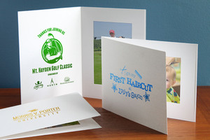 Custom white 4x6 photo folders with logo imprints in green, blue, and gold foils