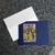 Blue wallet photo card lies on a granite countertop with a white mailing envelope.