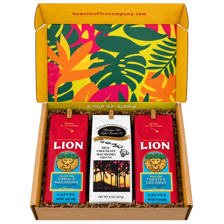 Open Hawaii Coffee Company gift box lined with tropical floral pattern, holding three ground coffee bags: Lion Vanilla Macadamia, Hawaiian Isles Milk Chocolate Macadamia, and Lion Toasted Coconut