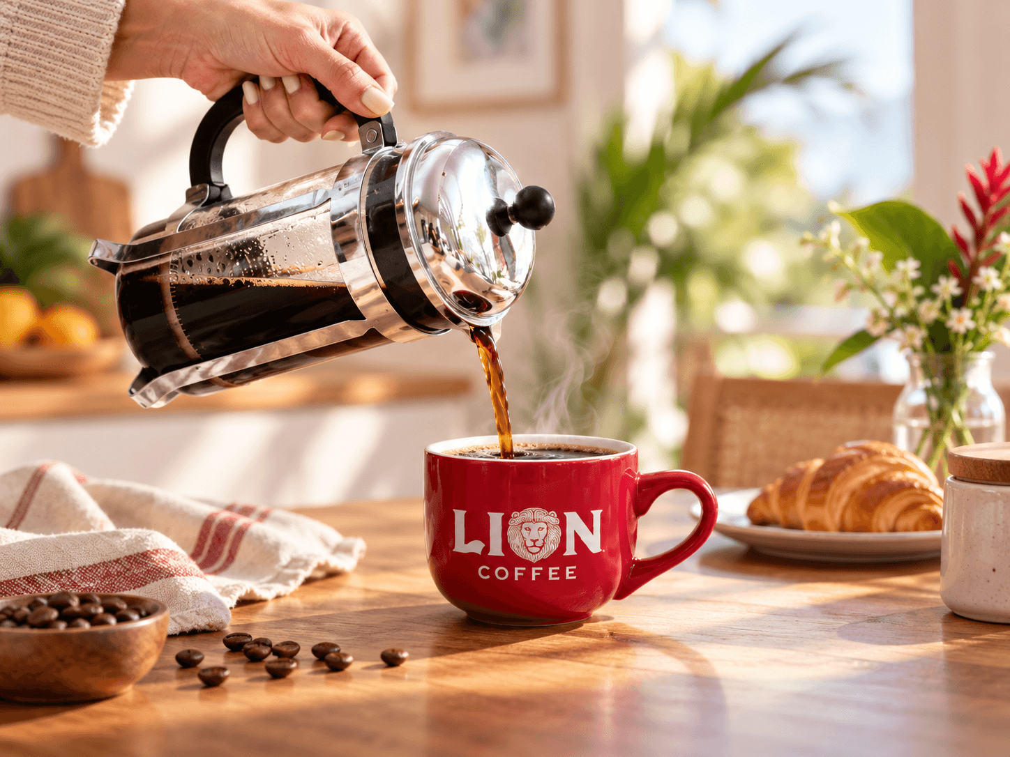 Coffee pouring from a French press into a red Lion Coffee mug