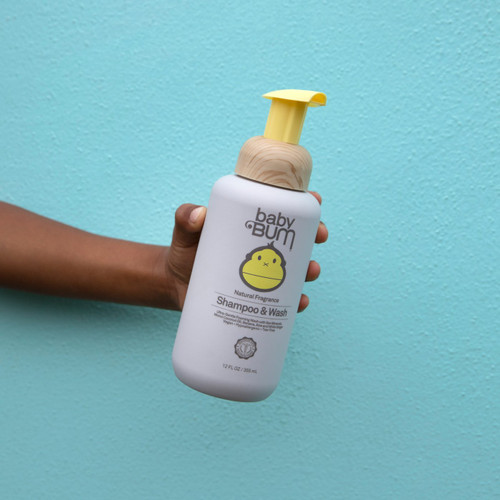 Sun Bum Baby Foaming Shampoo & Wash 355ml bottle being held on blue background
