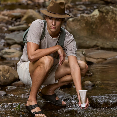 Natio For Men Purifying Facial Scrub 100g man in an outdoor setting holding the product