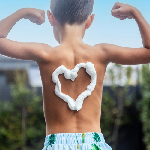 A person's back with a heart shape drawn in white sunscreen against a bright blue sky.