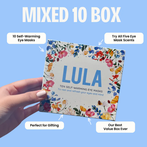 A hand holds a box of LULA brand self-warming eye masks, featuring a floral design and text highlighting "Mixed 10 Box," "10 Self-Warming Eye Masks," "Try All Five Eye Mask Scents," "Perfect for Gifting," and "Our Best Value Box Ever."