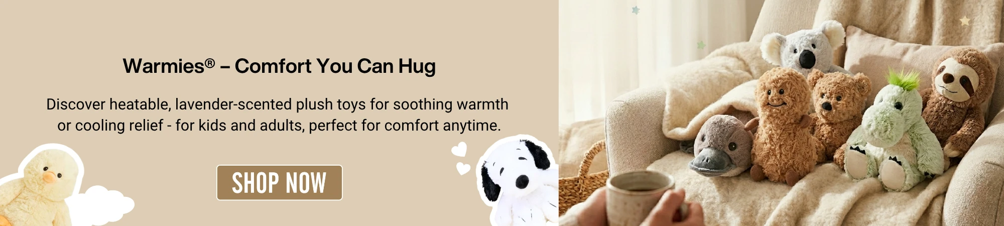 A digital promotional banner for Warmies plush toys. On the left, a tan background features the heading 'Warmies® – Comfort You Can Hug' followed by text describing heatable, lavender-scented plush toys for kids and adults. A 'SHOP NOW' button sits in the center, flanked by a yellow chick and a white dog plushie. On the right, a cozy lifestyle photo shows a group of Warmies—including a platypus, peanut, bear, koala, dragon, and sloth—nestled on a cream-colored armchair with a fuzzy blanket, while a person in the foreground holds a warm mug."