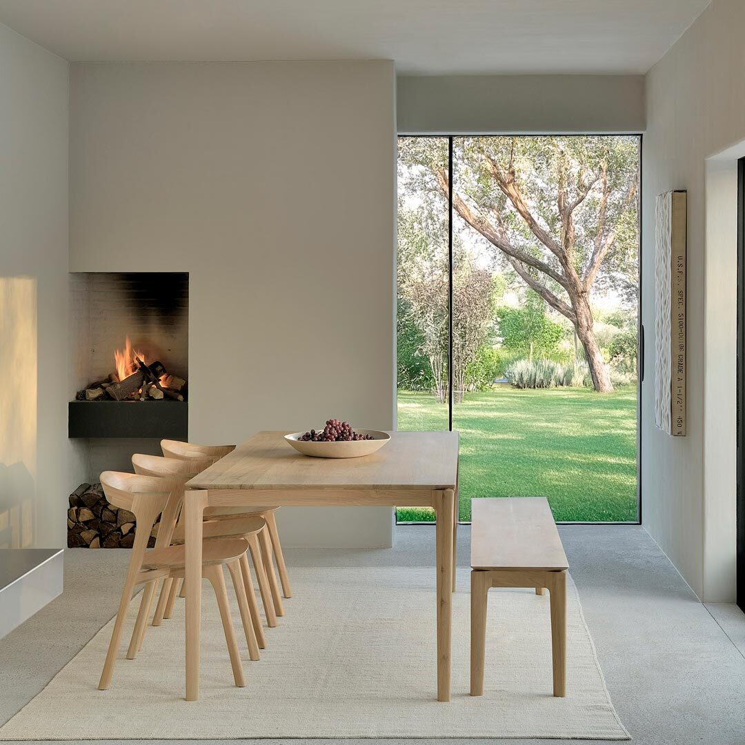 A serene dining space featuring the Ethnicraft Bok Oak table, paired with the matching bench and sculptural chairs – timeless, functional design with natural warmth.