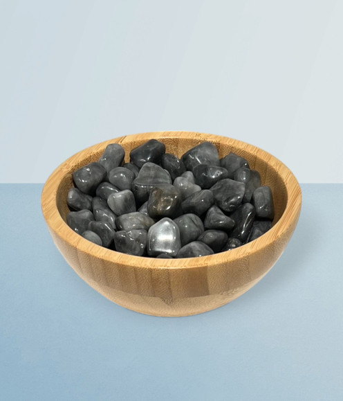 Cats Eye - bowl of tumbled pieces, against a cool blue background.