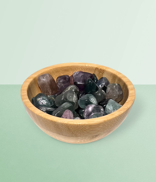 Rainbow Fluorite - bowl of tumbled pieces, against a cool green background.