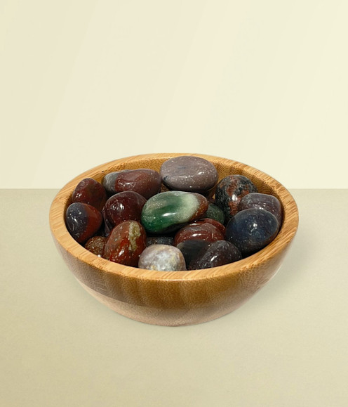 Ocean Jasper - a bowl of assorted tumbled pieces, against a warm yellow background.