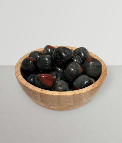 Bloodstone - a bowl of assorted tumbled pieces, against a light-grey coloured background.