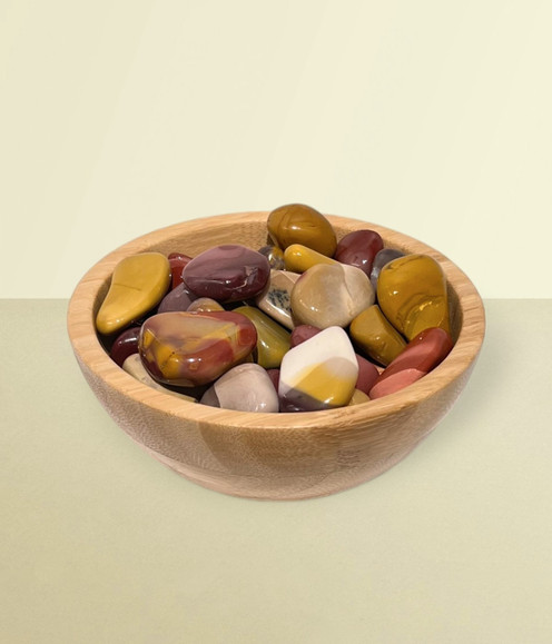 Mookaite - a bowl of assorted tumbled pieces, against a warm yellow background.
