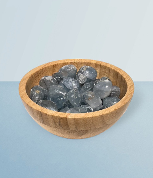 Celestite - bowl of tumbled pieces, against a cool blue background.